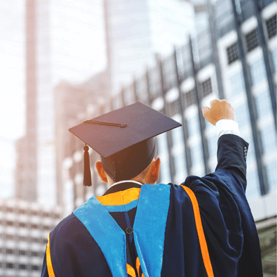 college graduate in cap and gown pumping his fist in excitment after graduating