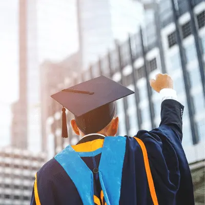 college graduate in cap and gown pumping his fist in excitment after graduating